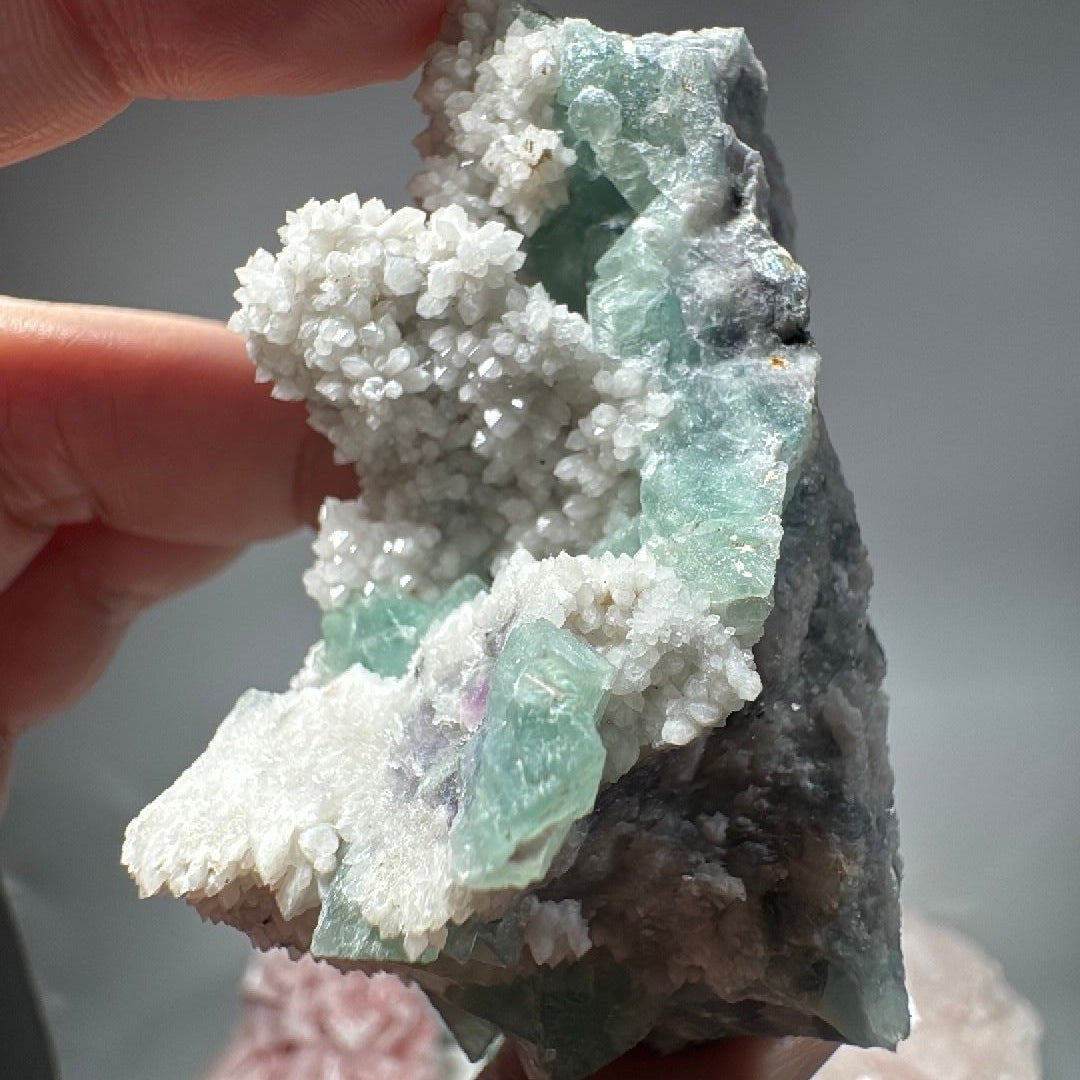 The 2.96 oz specimen held up close, green cubes glowing where light passes through