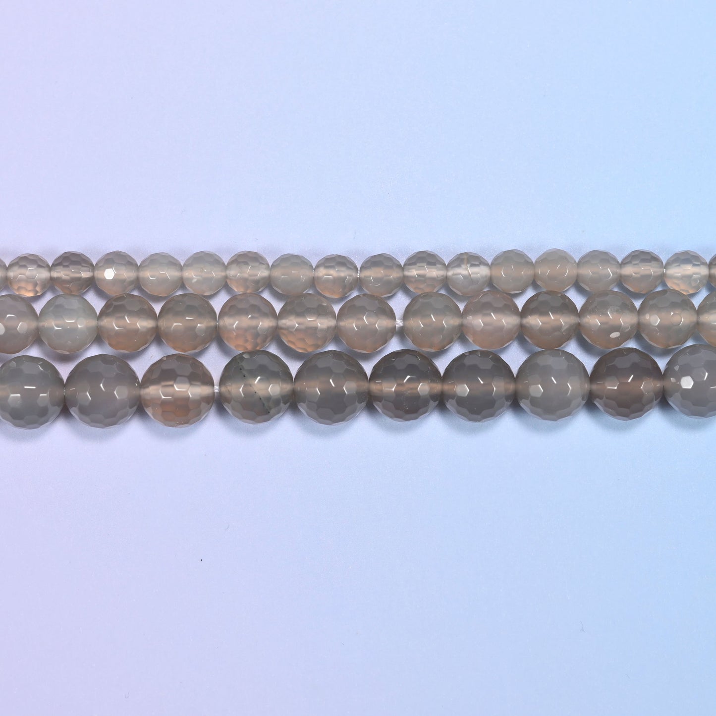 Full 15-inch strand of gray agate round beads laid out for jewelry making.