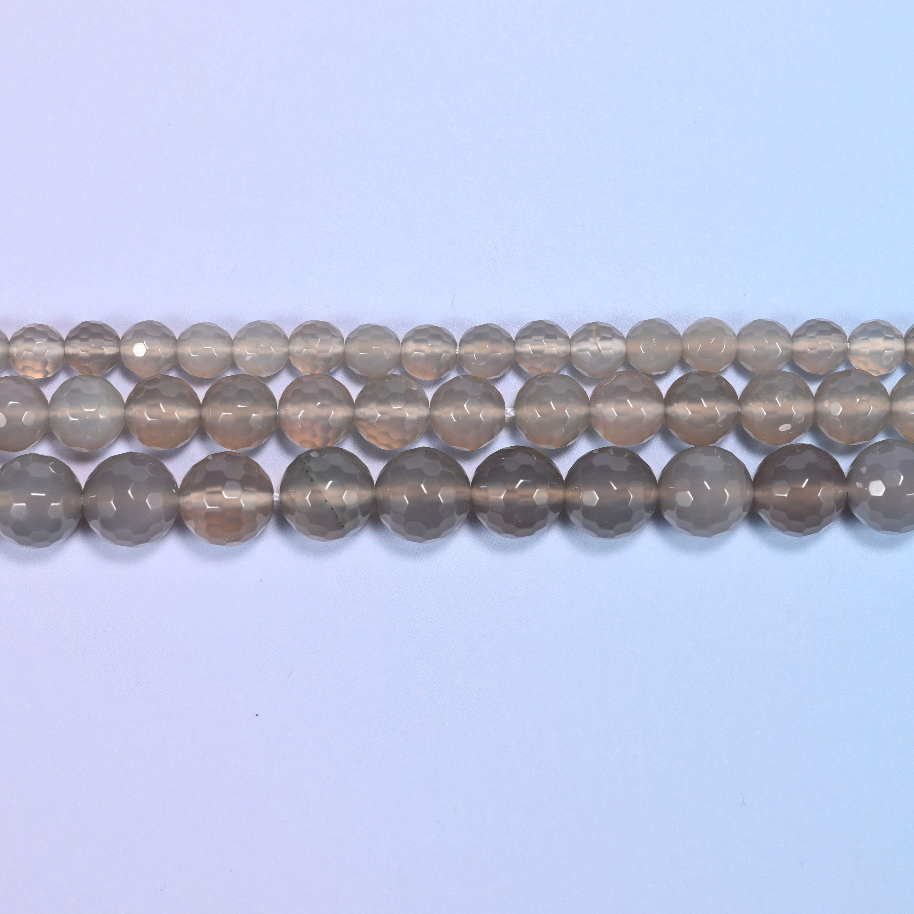 Full 15-inch strand of gray agate round beads laid out for jewelry making.