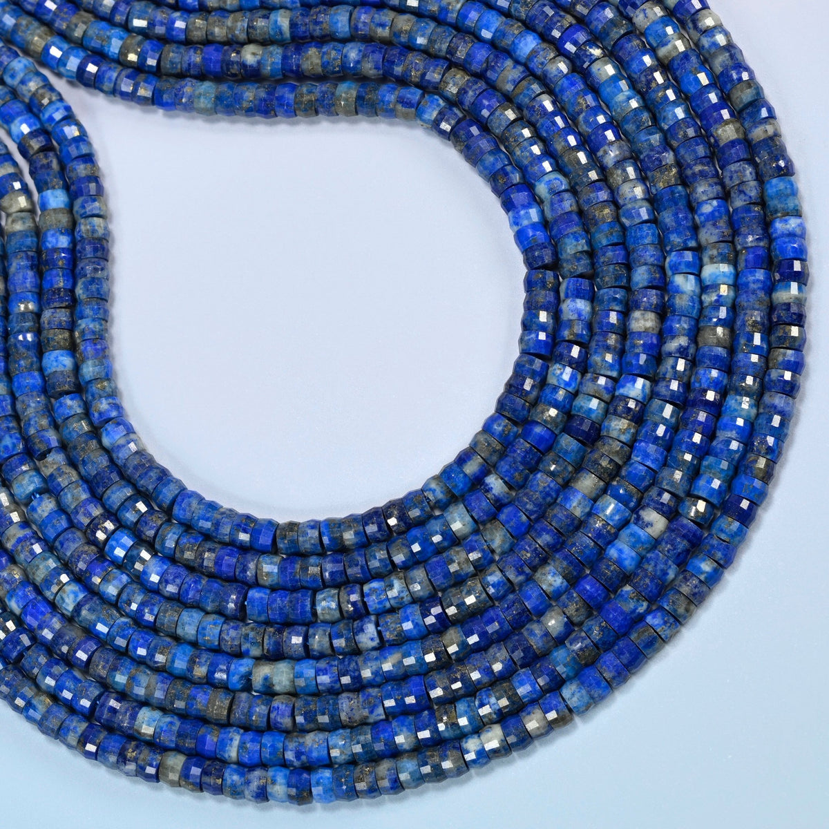 Lapis faceted heishi disc beads curved into an open loop, royal blue beads with white and gray patches