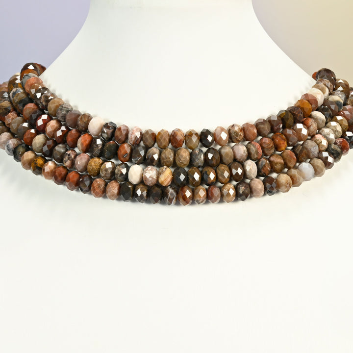 Petrified wood faceted rondelle strands arranged as a layered collar on a white display bust, earth tones across the neck