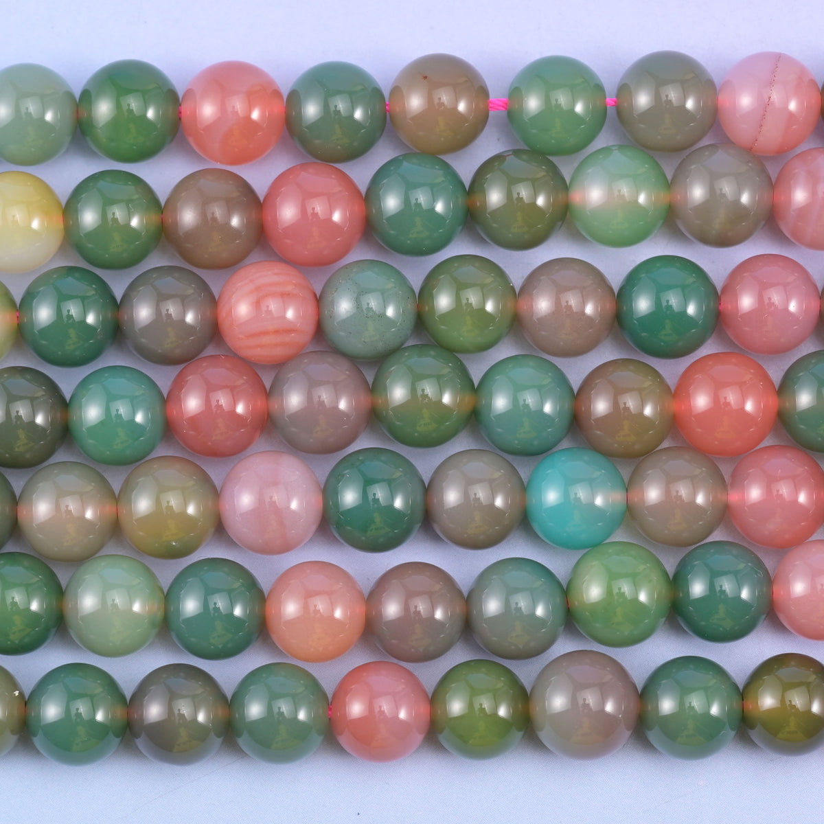 Green Yanyuan Agate smooth round beads in close parallel rows, colour proportion changing along each 14 inch strand