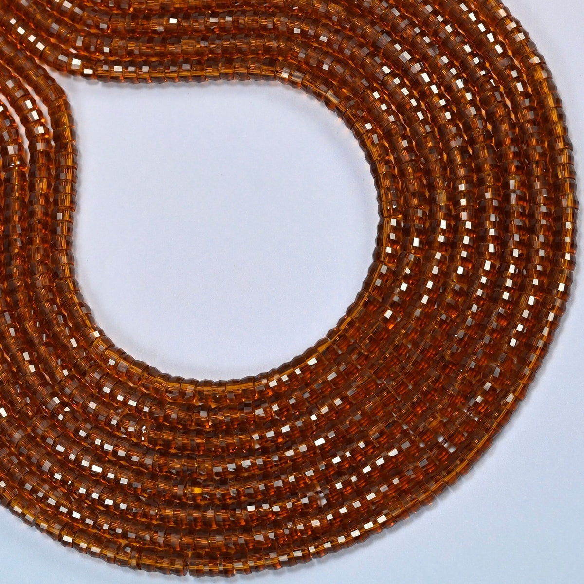 Brown glass faceted heishi disc beads curved into an open loop, transparent amber brown beads