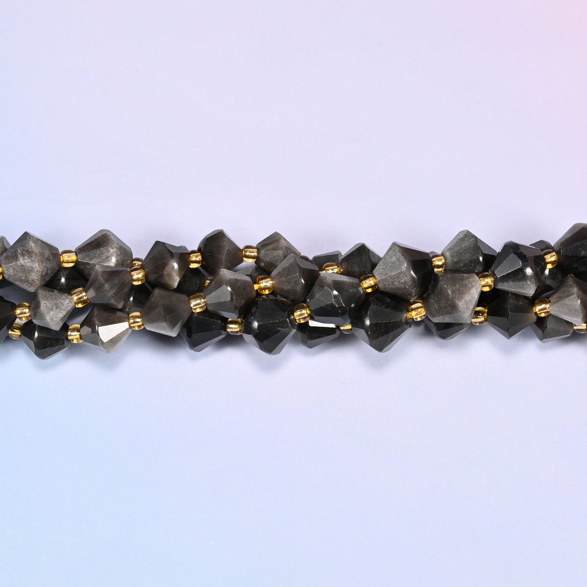 Silver obsidian bicone beads shown as a single strand laid straight across, darker near-black beads beside paler silvered ones.