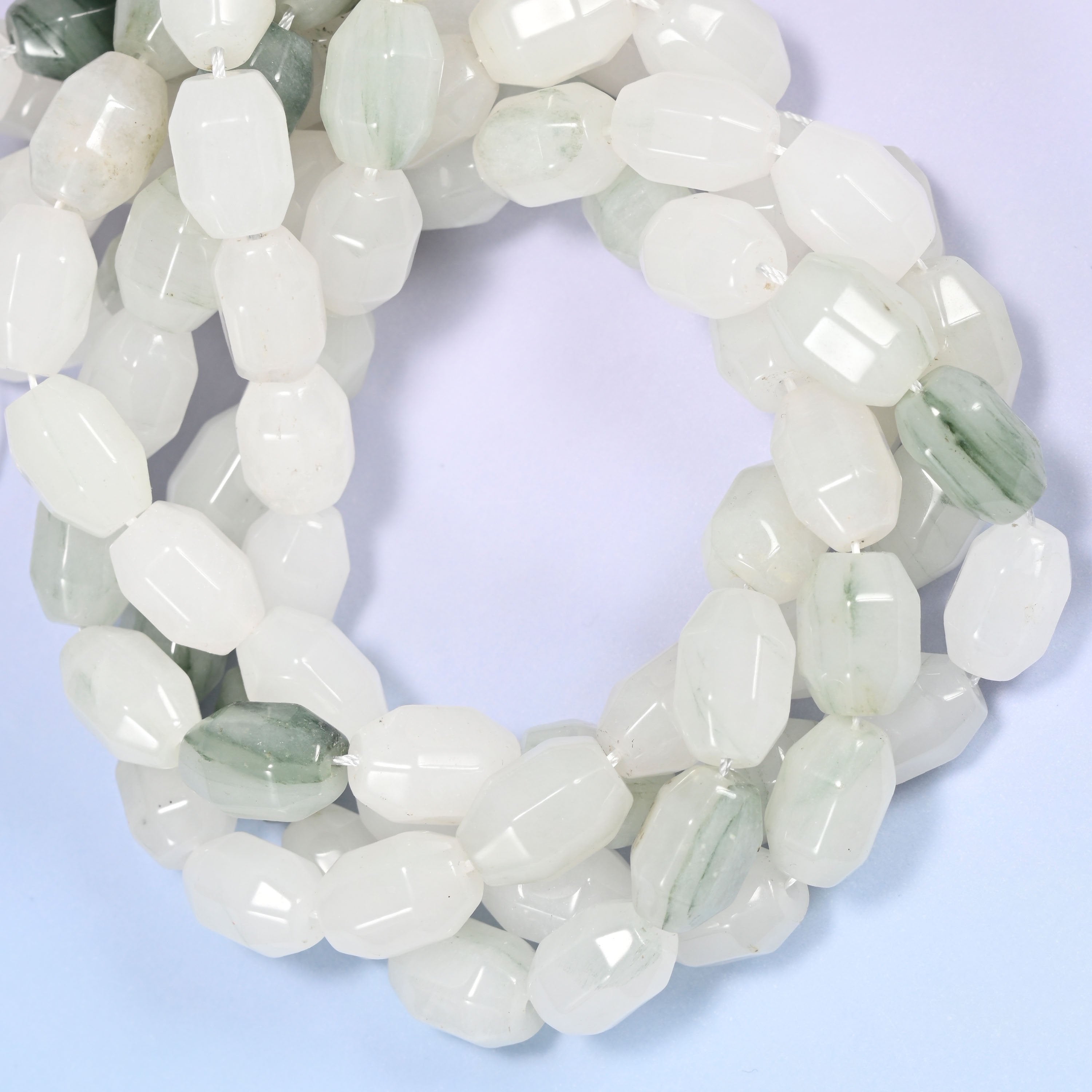 Close-up circular coil of Tianshan Jade faceted barrel bead strands with a penny in the center for size comparison.