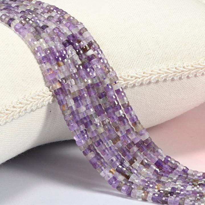 Amethyst faceted heishi disc beads 2x4mm, several strands draped over a white cushion