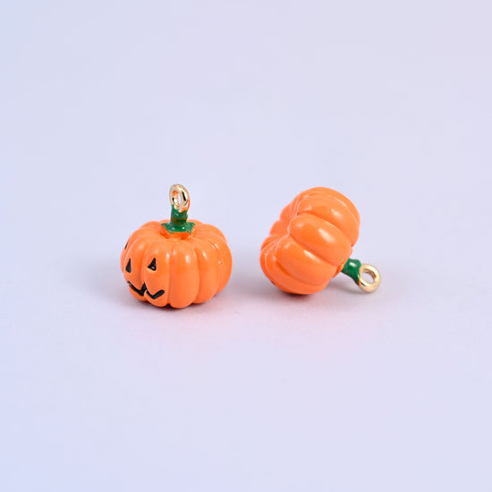 Enamel pumpkin charms, one facing forward and one turned to show the gold-tone ring at the stem.