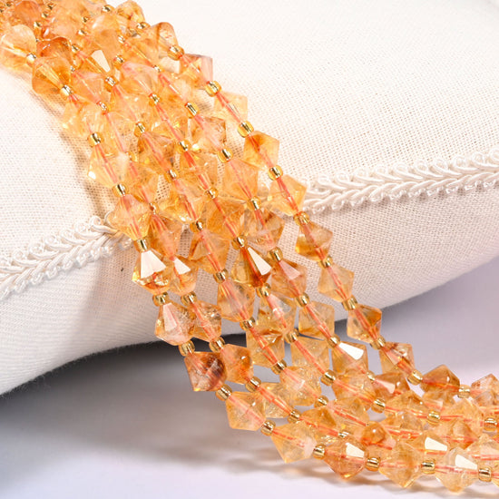 Citrine bicone beads laid out on the diagonal in several rows, warm translucent golden orange, a gold-tone spacer between every bead.