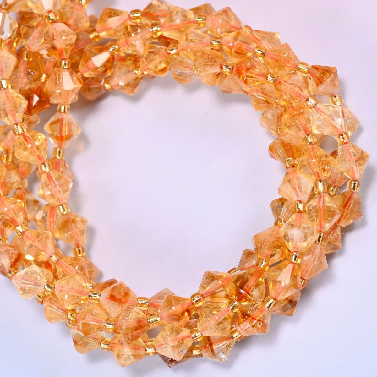 Citrine bicone beads coiled into a round ring of several strands, a warm golden glow running the length of the strand.
