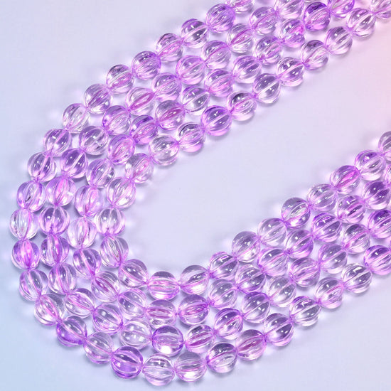Clear purple pumpkin glass beads, several strands laid in a wide sweeping curve across the frame.