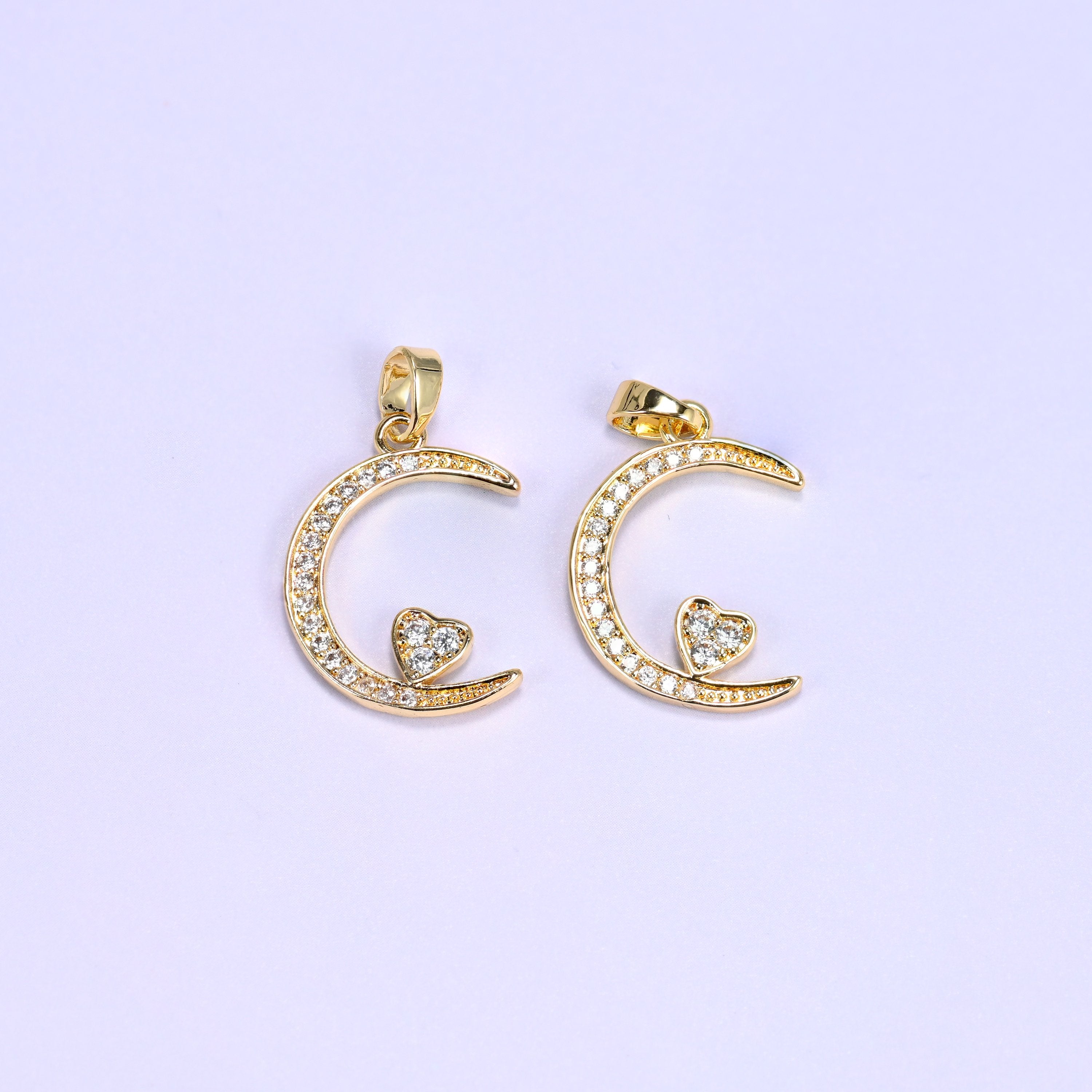Two gold moon heart zirconia charms placed side by side, each crescent moon paved in clear zirconia with a heart accent.