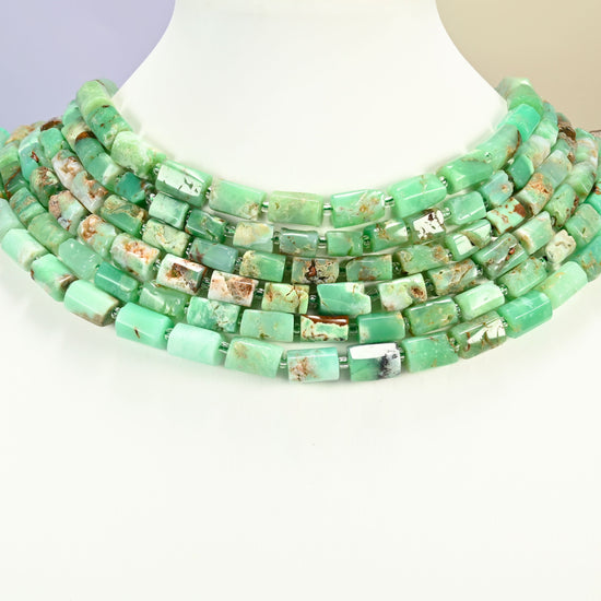 Australian jade faceted tube strands arranged as a layered collar on a white display bust, mint and apple green beads across the neck