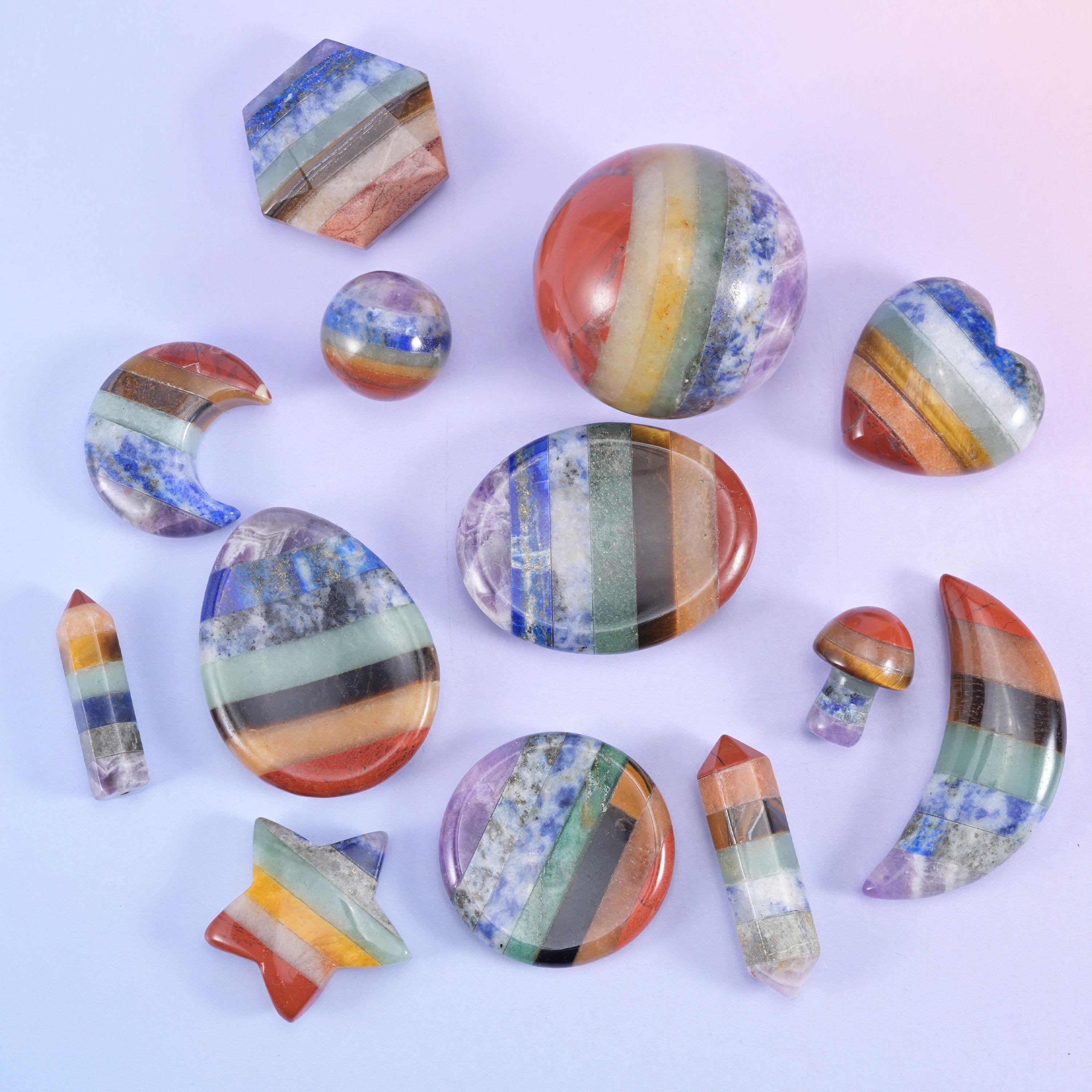 Assorted rainbow banded stone carvings including star, hexagon, sphere, coin and point shapes arranged on a pale lilac background