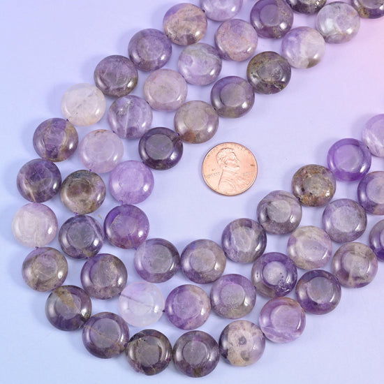 Amethyst coin beads arranged around a US penny for size comparison