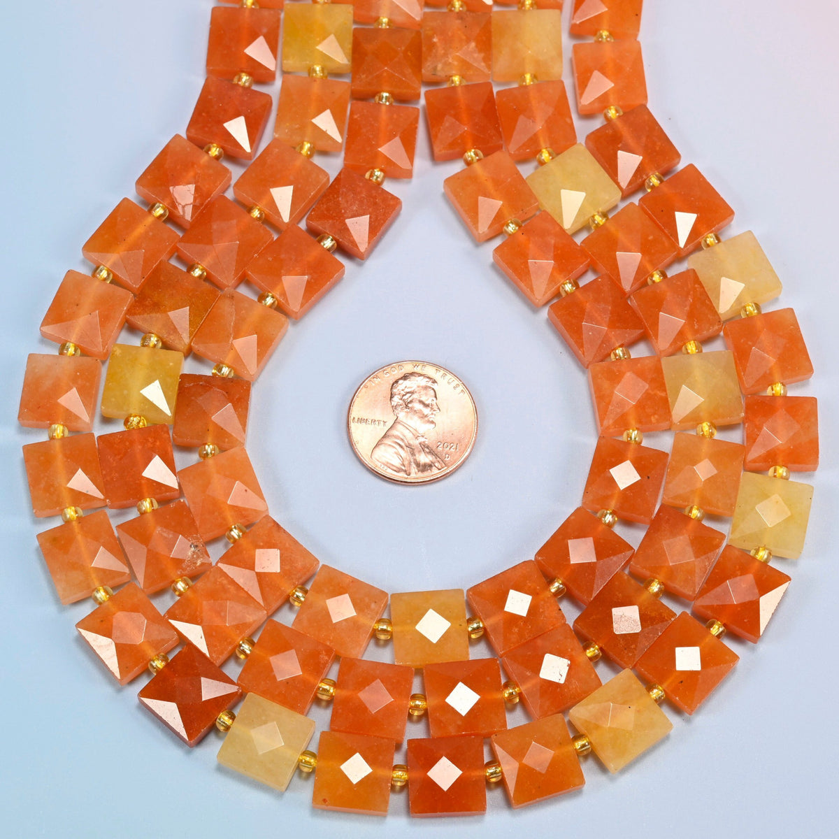 Natural red aventurine faceted flat square strands formed into a teardrop loop around a US penny for scale