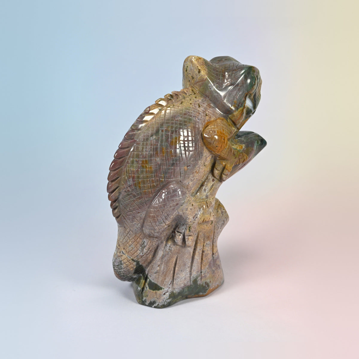 Rear three-quarter view of the natural ocean jasper chameleon carving on its branch base