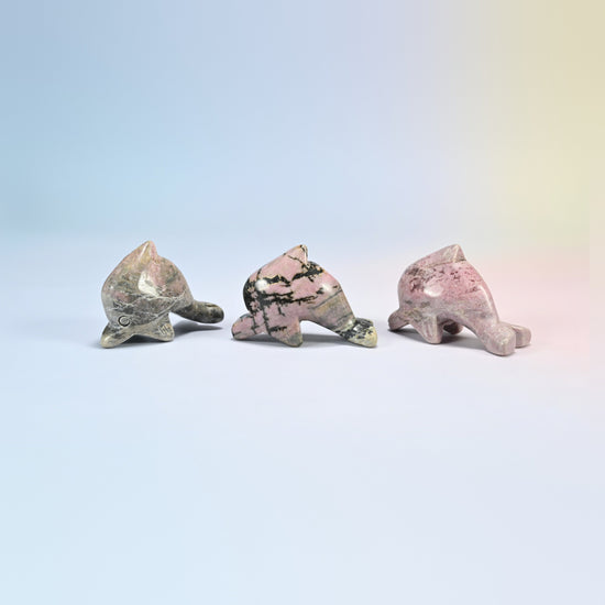 Three rhodonite dolphin crystal carvings, pink natural stone with black veins