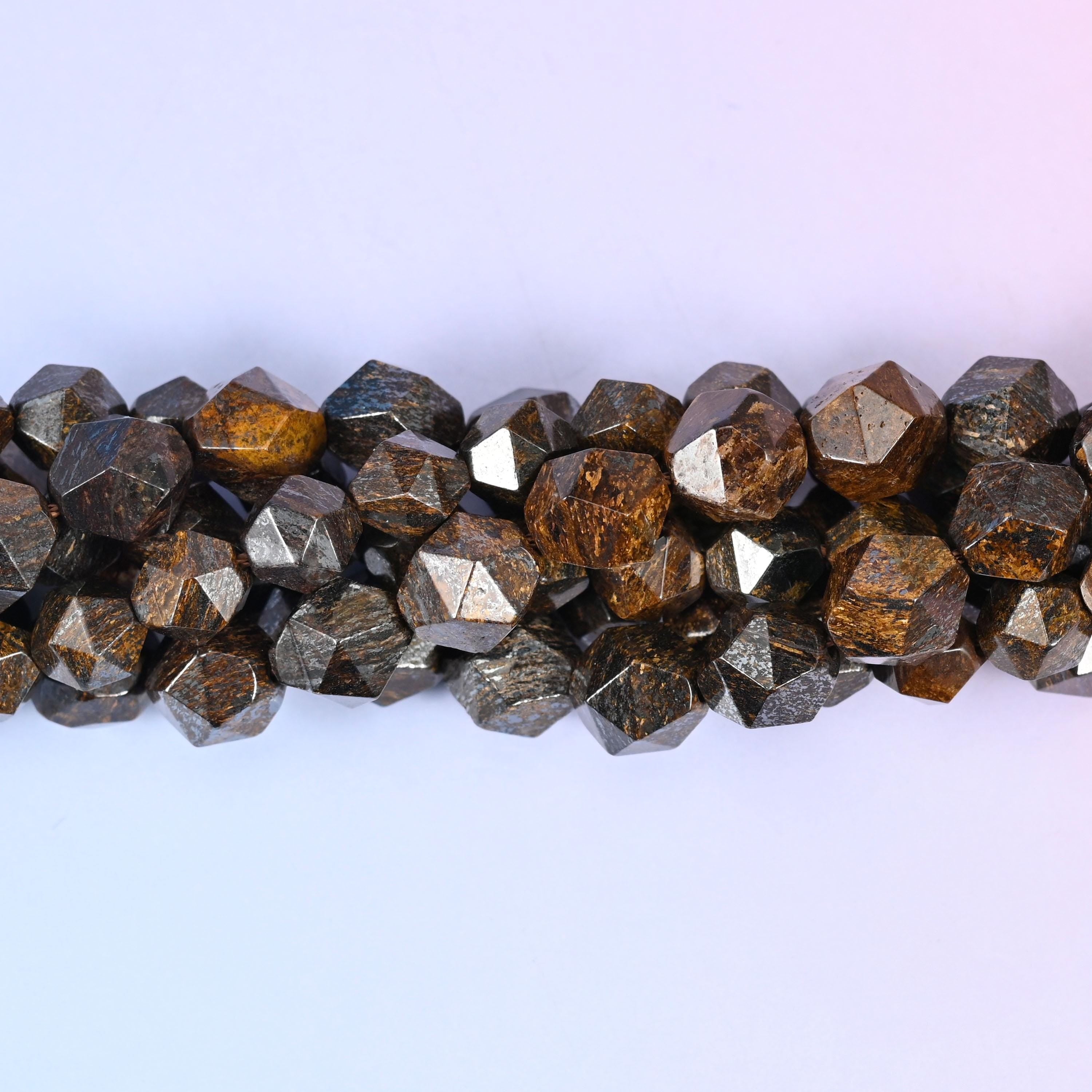 Warm bronze-brown rounds cut into sharp diamond star facets, each flat plane catching the light with a metallic shimmer over tan and cocoa mottling