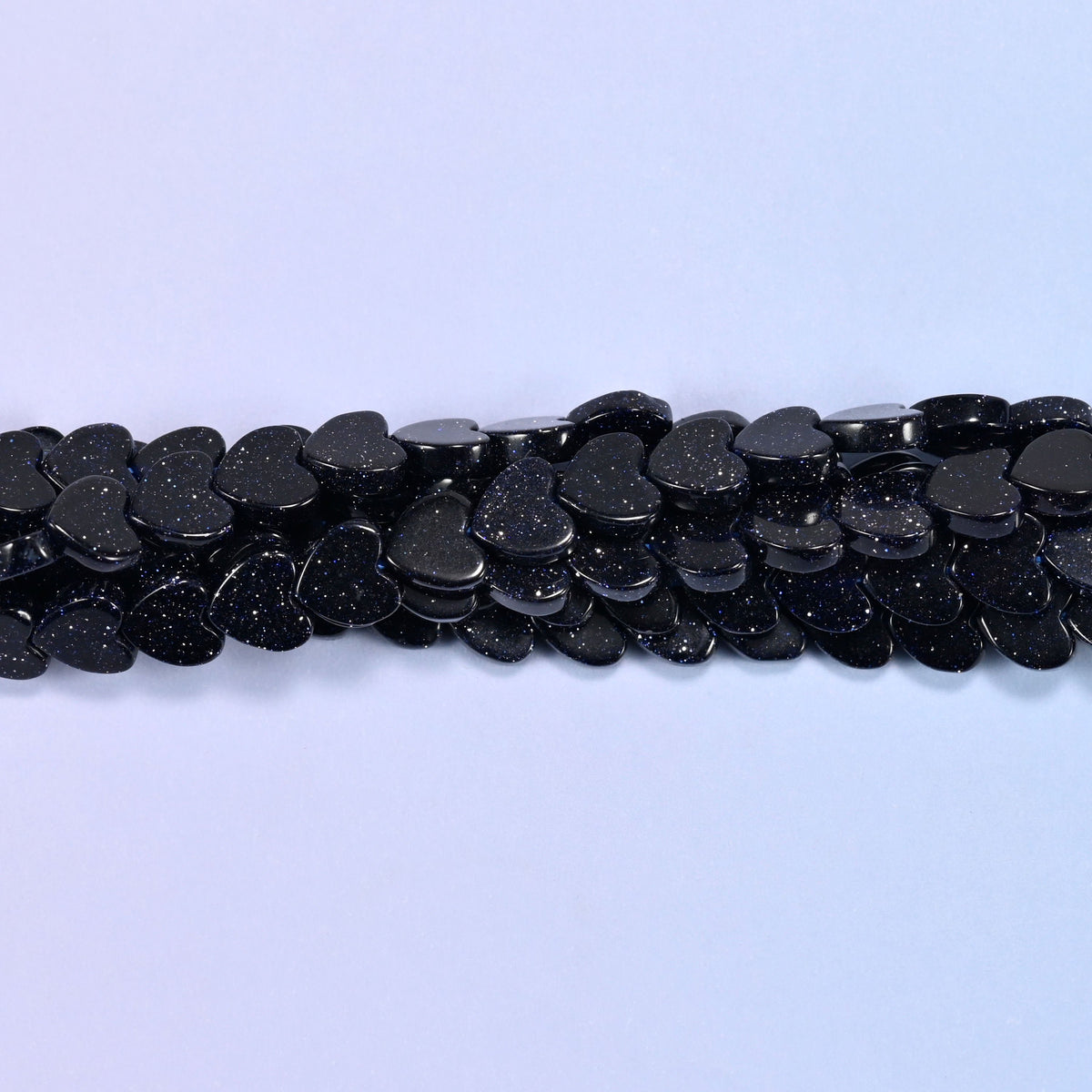 Deep midnight blue flat hearts shot through with tiny metallic sparkles, so the strand reads almost black at a distance and glitters like a night sky up close.