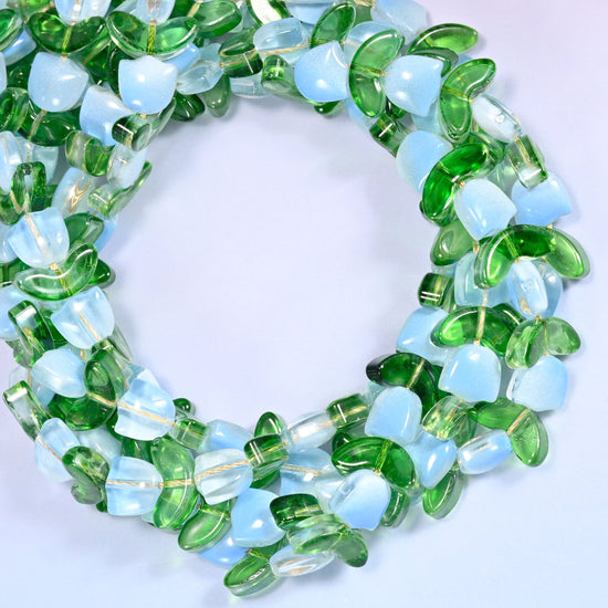 Wide circular coil of light blue tulip and green leaf glass beads on a lavender background, showing the full wreath.