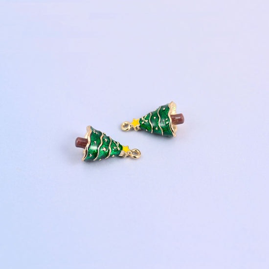 Two christmas tree charms lying at an angle, green enamel branches with fine gold garland lines.