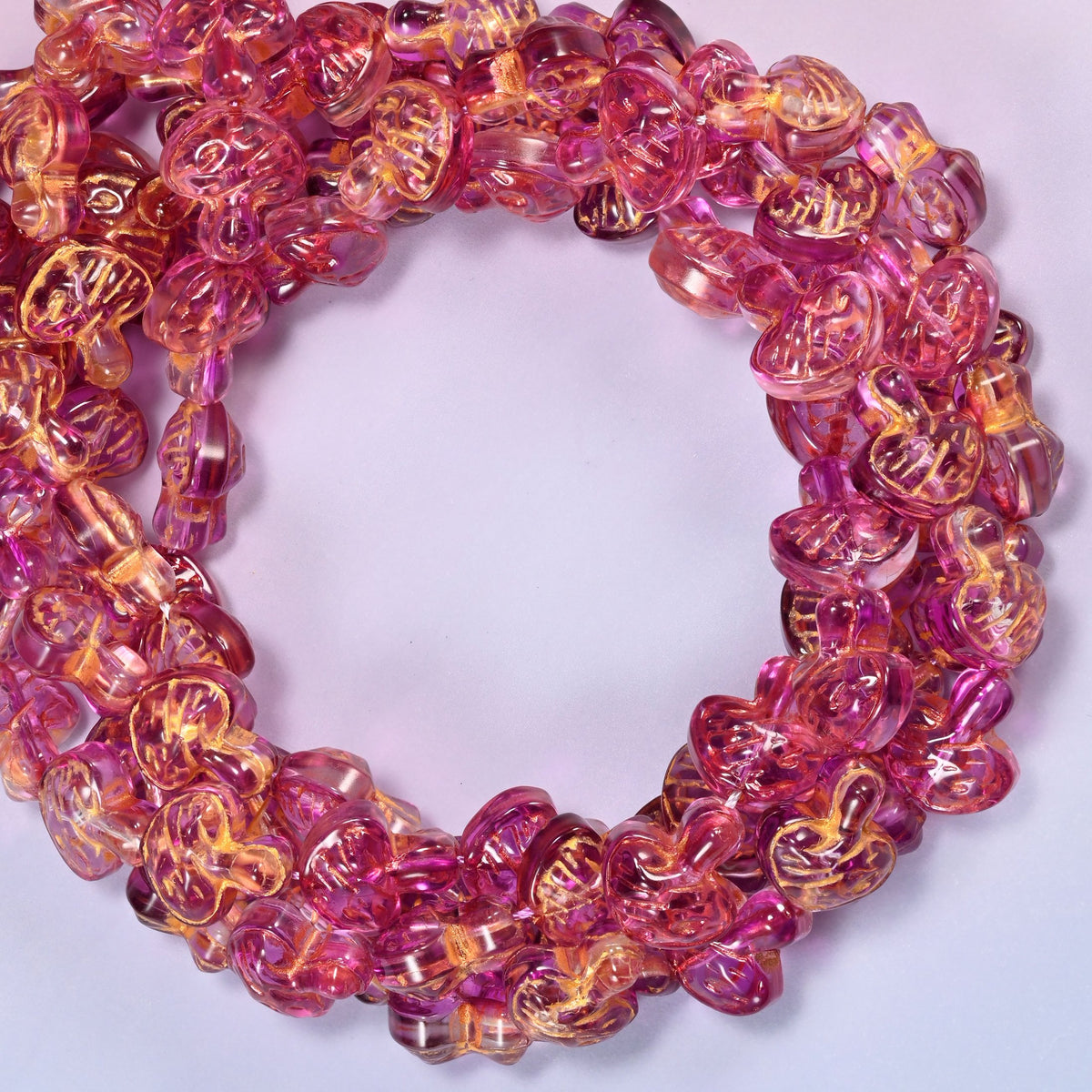 Pink gold flat mushroom glass beads coiled into a densely packed ring with a small round opening.