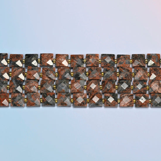 Several strands of natural red sesame jasper faceted flat square beads laid in straight rows