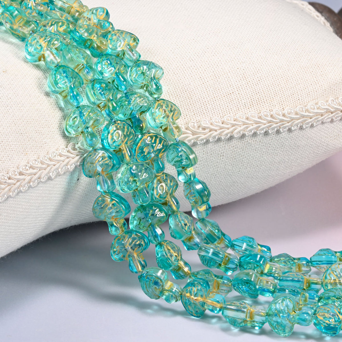 Aqua gold flat mushroom glass beads, 13x12mm pressed glass, several strands draped forward in rows.