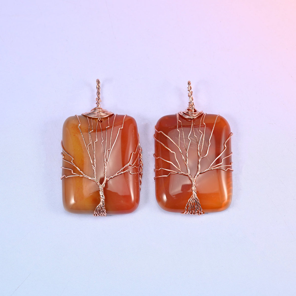 Rectangle Gemstone Tree of Life Pendant in banded red-orange agate, two pieces showing how the colour bands run behind the copper branches.