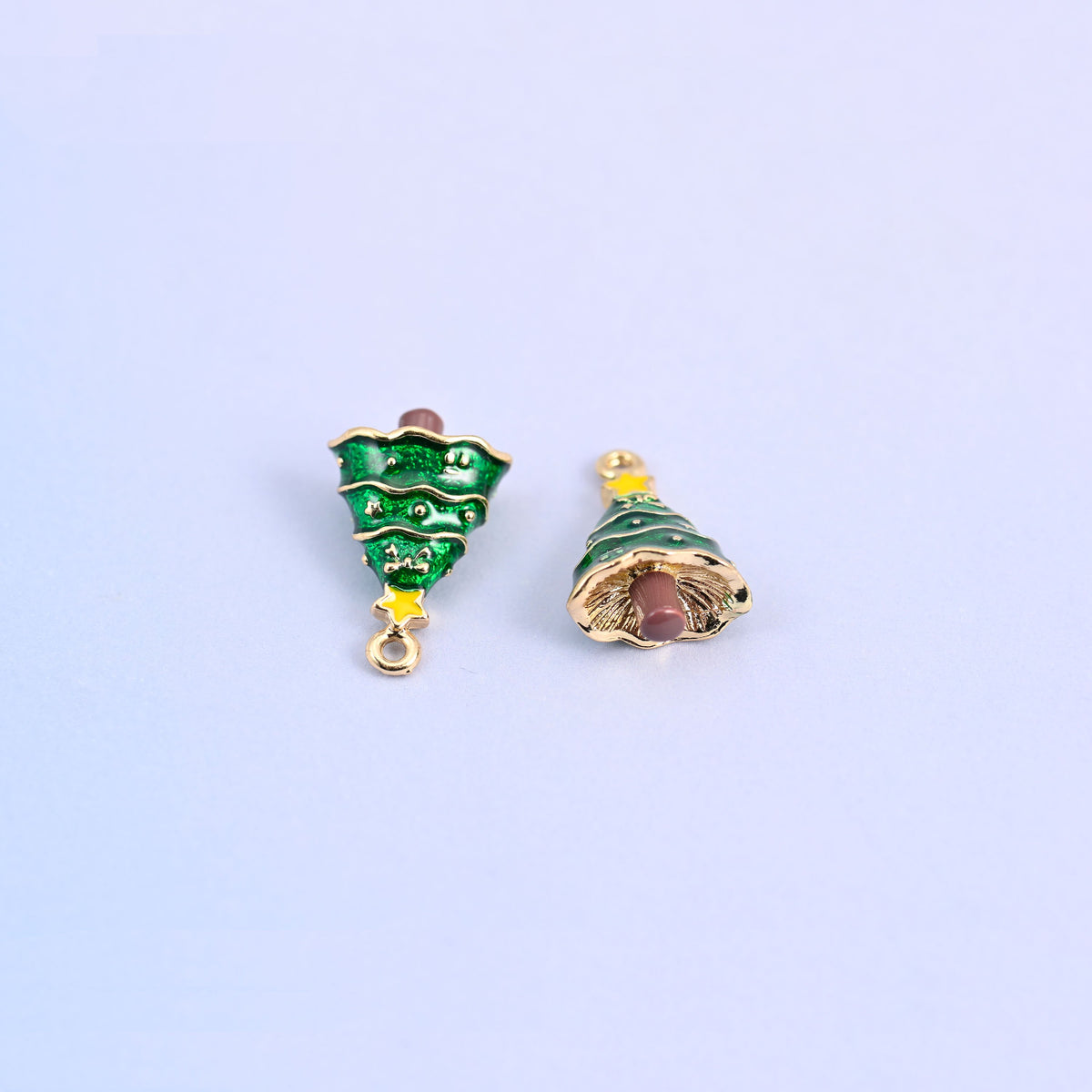 Pair of christmas tree charms, one turned to show the gold-tone underside of the skirt.