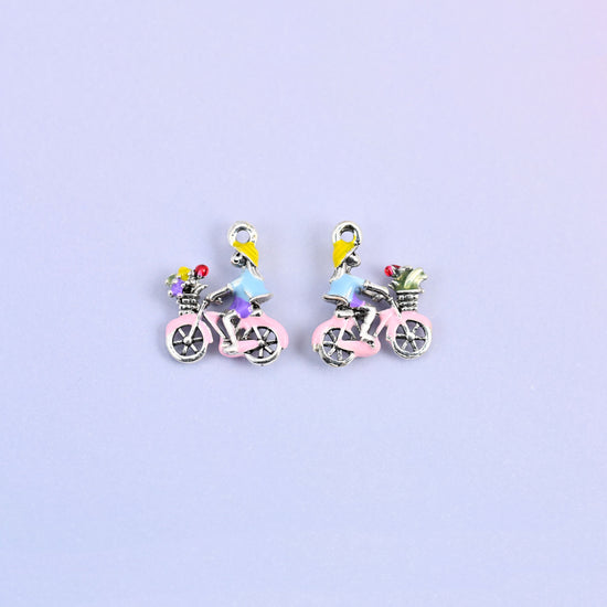 Two bicycle charms side by side, enamel detail on 18K white gold plated brass.