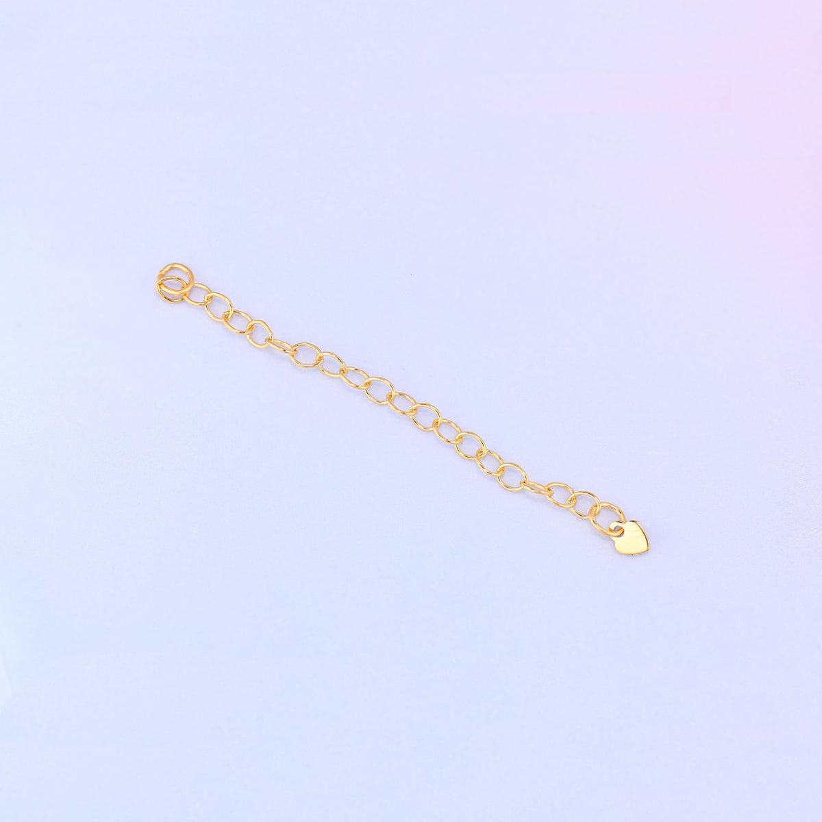 14K gold filled heart chain extender laid diagonally, cable-link chain with a jump ring loop at one end and a small heart charm at the other.