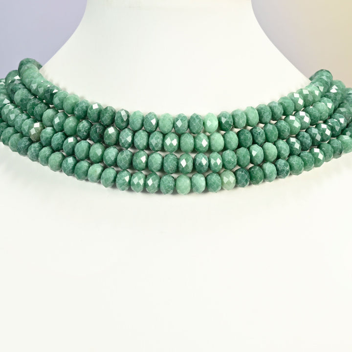 Natural green jade faceted rondelle strands arranged as a layered collar on a white display bust, mottled green beads across the neck
