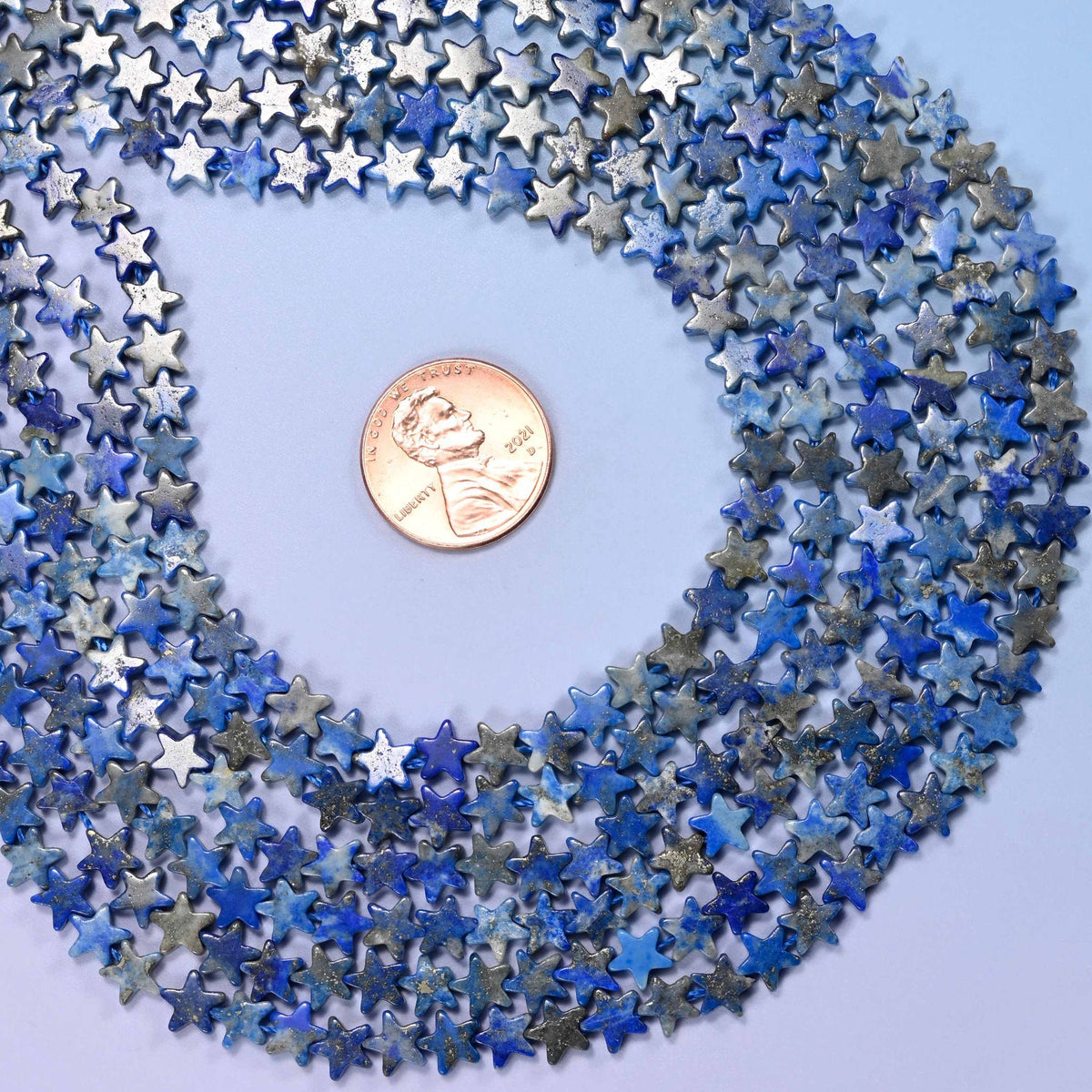 Lapis lazuli flat star beads, tiny five-pointed stars in denim and royal blue marbled with grey and chalk white, cut flat so they lie face-up in a strung row.