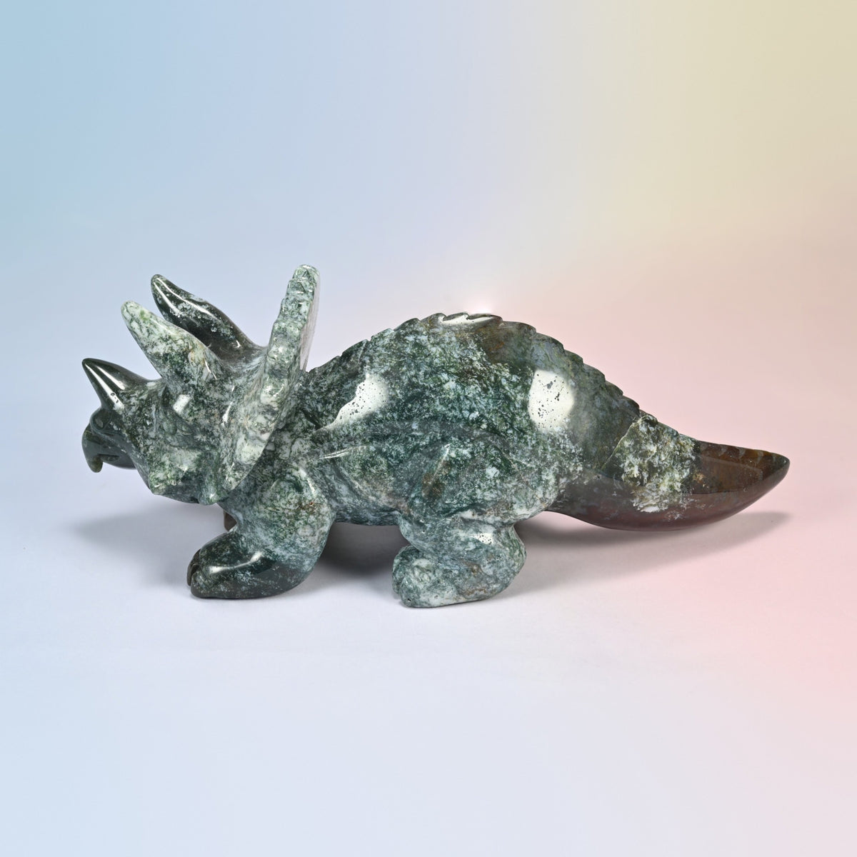 Left side of the natural Indian agate triceratops, mossy green and white body with a brown tail tip
