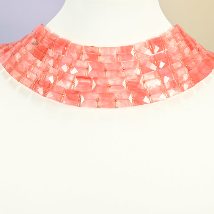Melon quartz faceted flat square strands arranged as a layered collar on a white display bust, pink beads across the neck