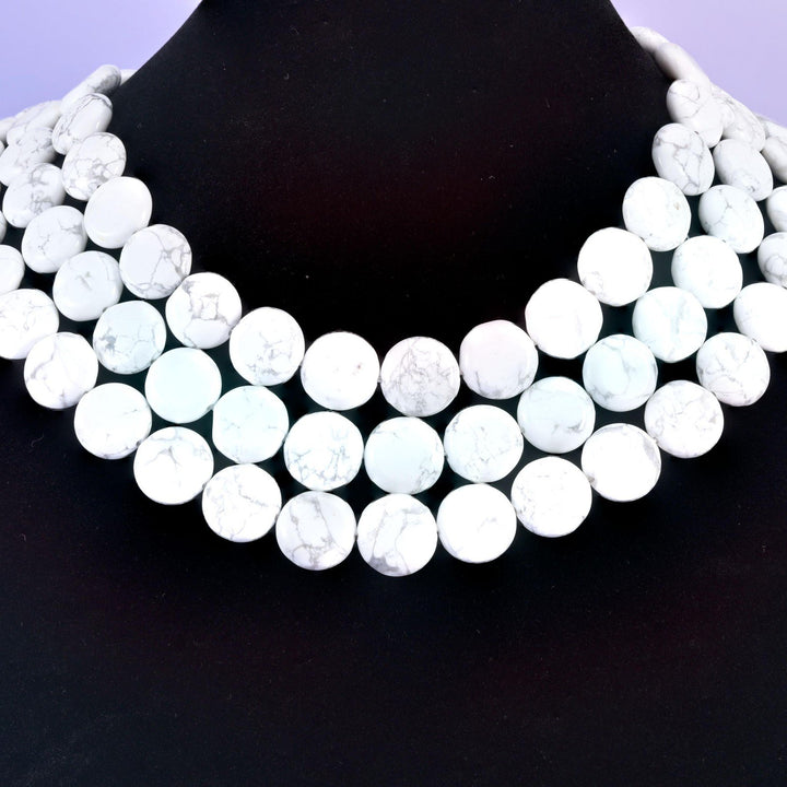 White Howlite coin beads against a black background, flat 15mm discs in bright chalk white