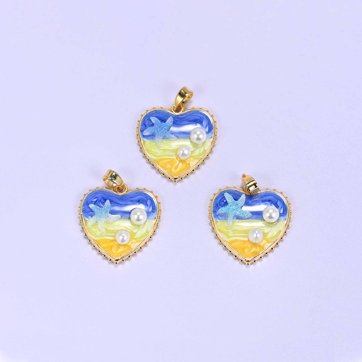 Enamel Heart Pendants in the blue colourway, three gold-plated charms grouped together with swirled blue-to-yellow enamel, a glitter starfish and faux pearls.