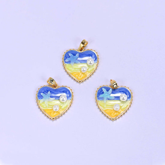 Enamel Heart Pendants in the blue colourway, three gold-plated charms grouped together with swirled blue-to-yellow enamel, a glitter starfish and faux pearls.
