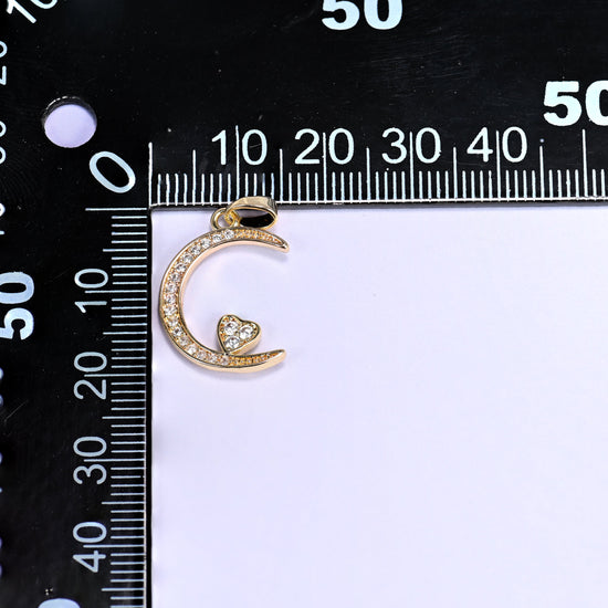 Gold moon heart zirconia charm on a black millimetre ruler, the crescent measuring roughly 20mm across.