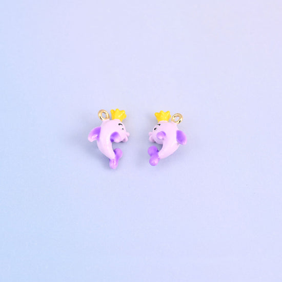 Two light purple dolphin charms with crowns, front and back, each wearing a yellow crown.