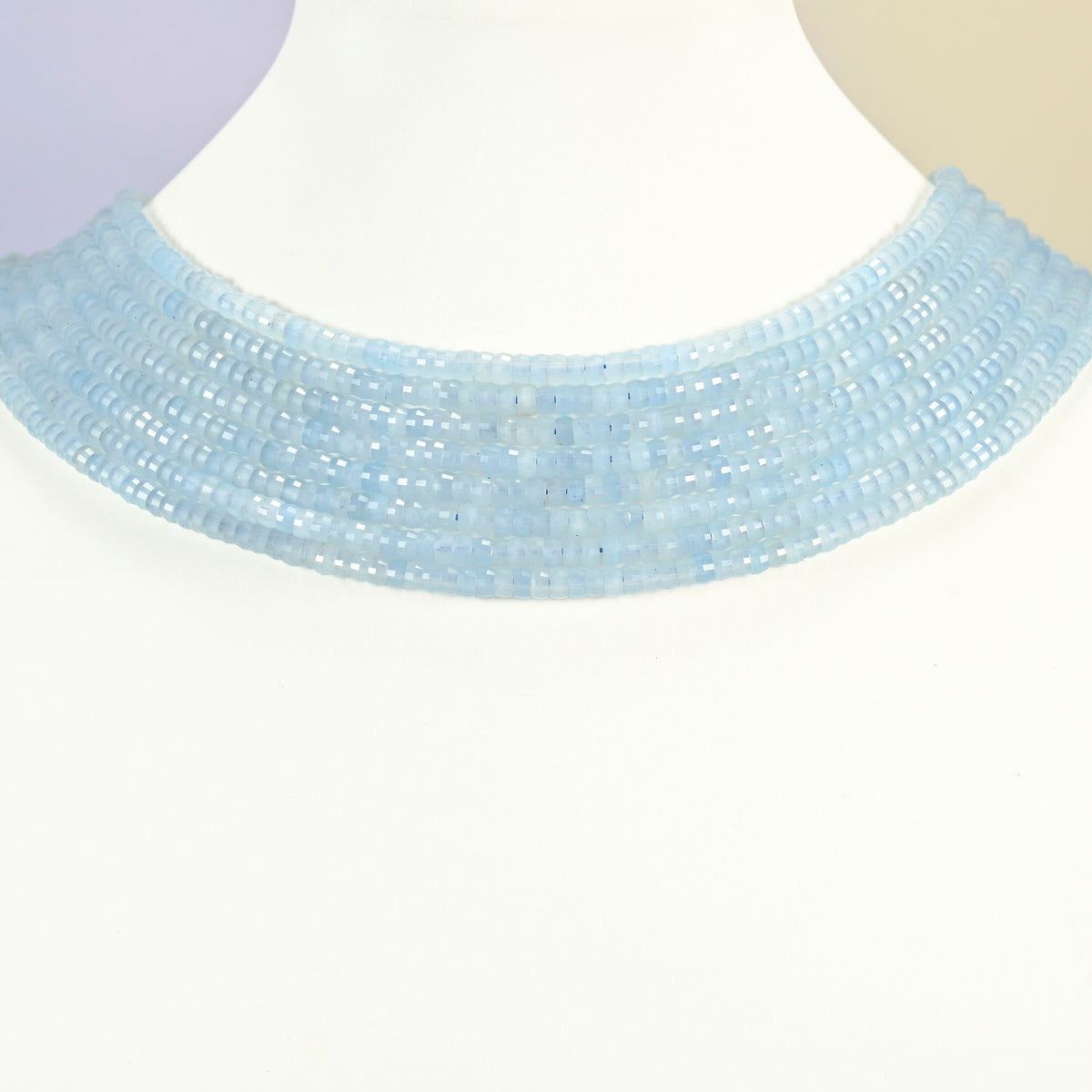Aquamarine chalcedony faceted heishi disc strands arranged as a layered collar on a white display bust, light blue beads across the neck