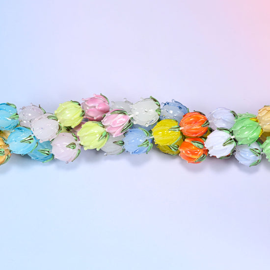 Wide circular coil of multicolor tulip bud lampwork glass bead strands forming a full wreath shape on a lavender and pink gradient background.