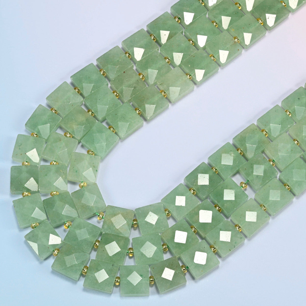 Natural green aventurine faceted flat square beads in several strands curved into a wide U, light green stone with a soft shimmer
