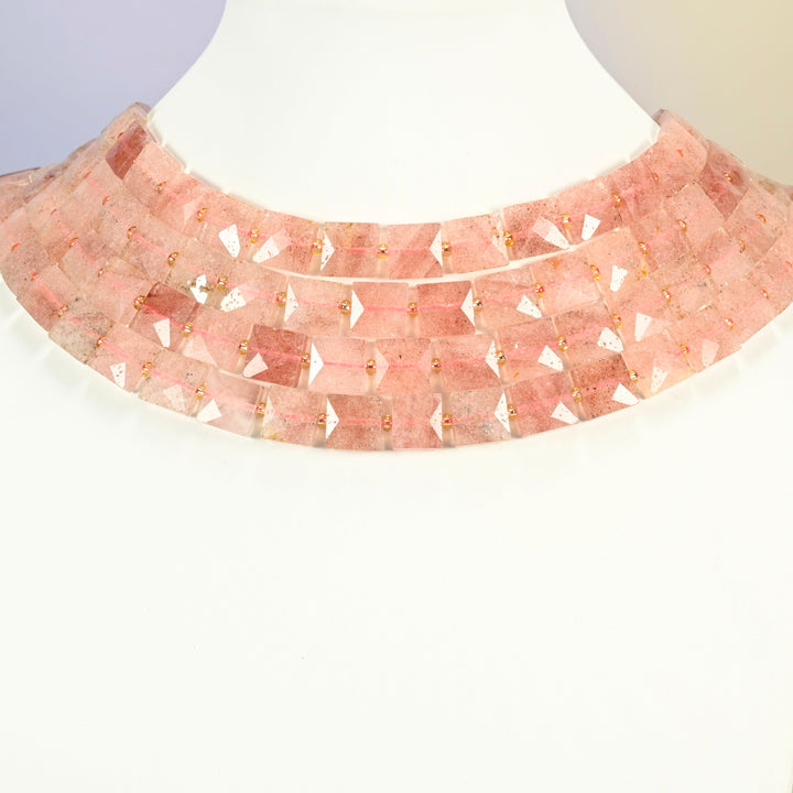 Natural strawberry quartz faceted flat square strands arranged as a layered collar on a white display bust, soft pink beads across the neck