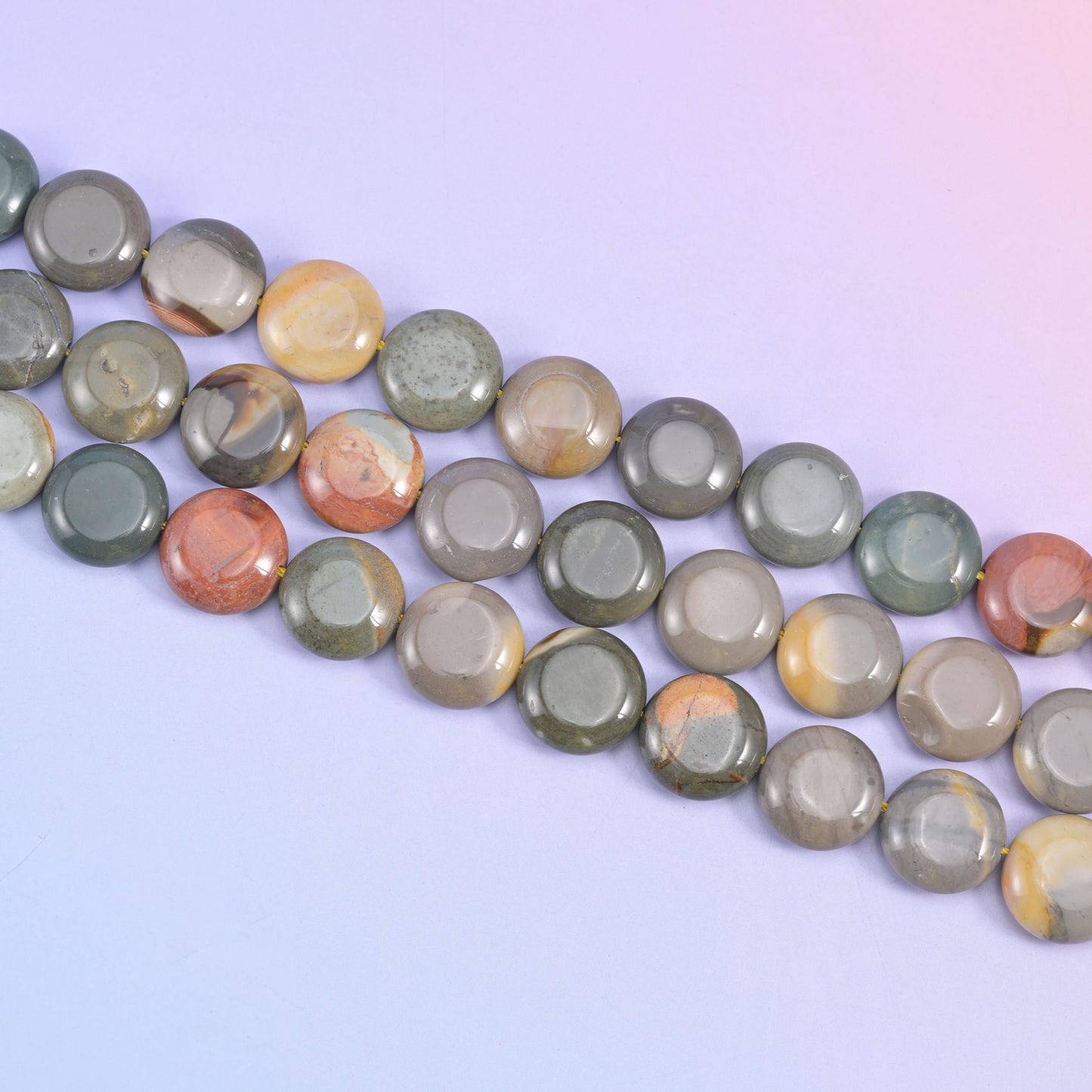 Angled row of 15mm picture jasper coins on pale lilac, grey beads broken by warm tan stripes
