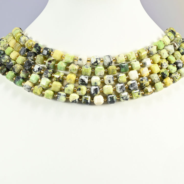 Yellow howlite faceted cube strands arranged as a layered collar on a white display bust, yellow, lime green and cream beads across the neck
