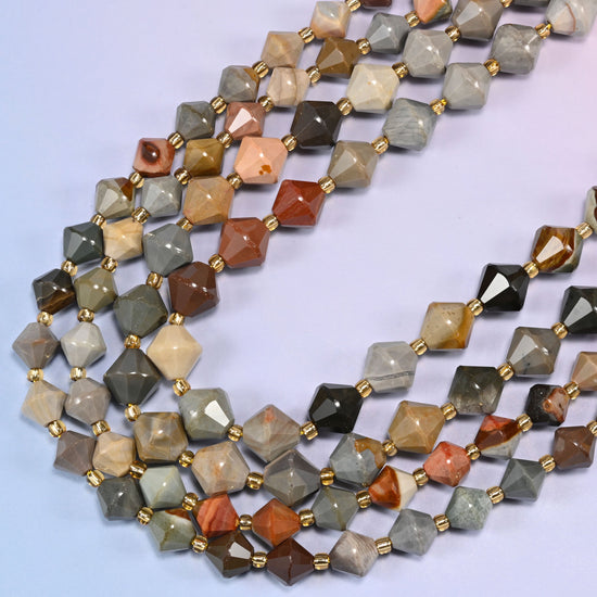 American Picture Jasper faceted bicone beads, 8mm and 10mm, arranged in a loose curved strand on a light lavender background.