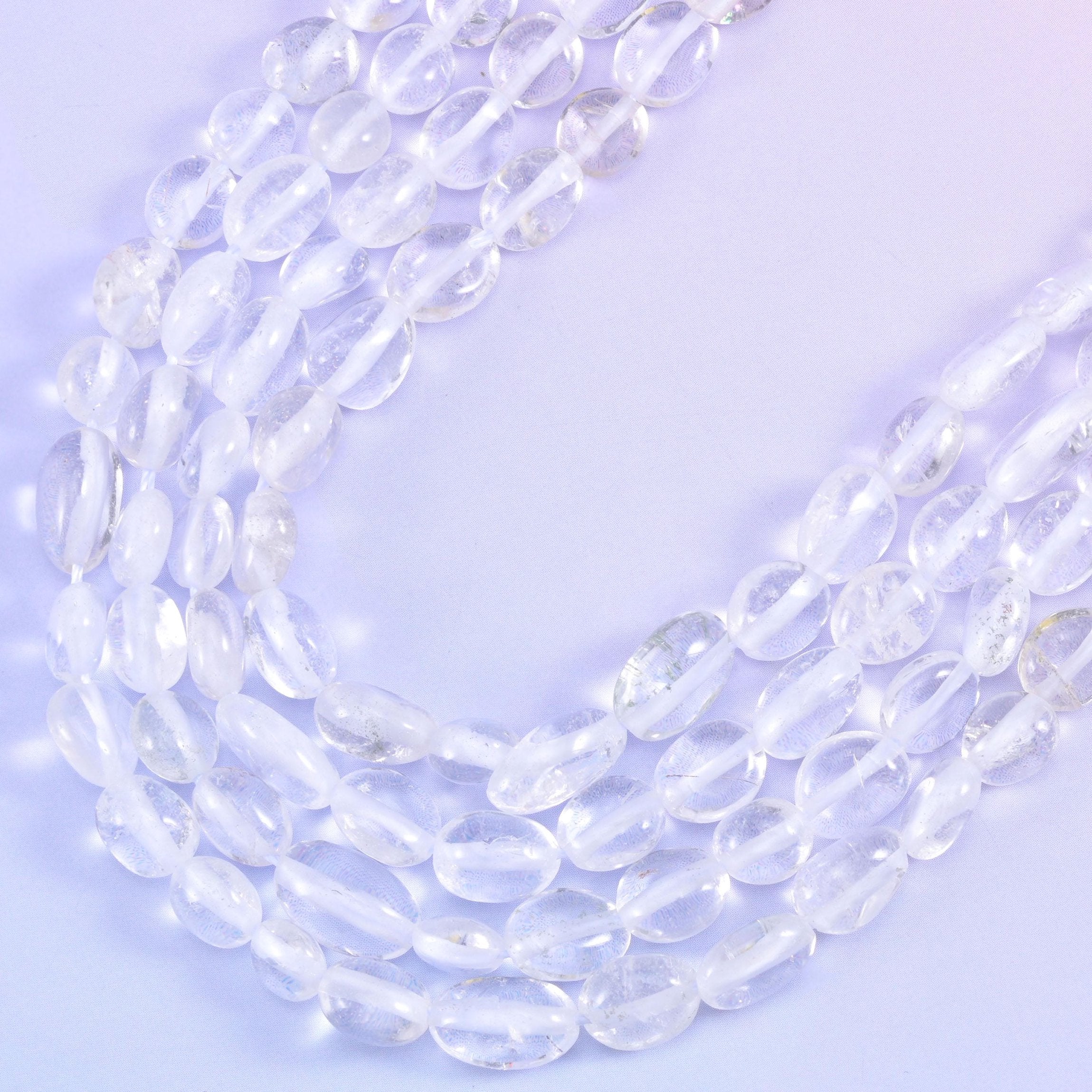 Strands curving into a soft V, colourless beads picking up the lilac background