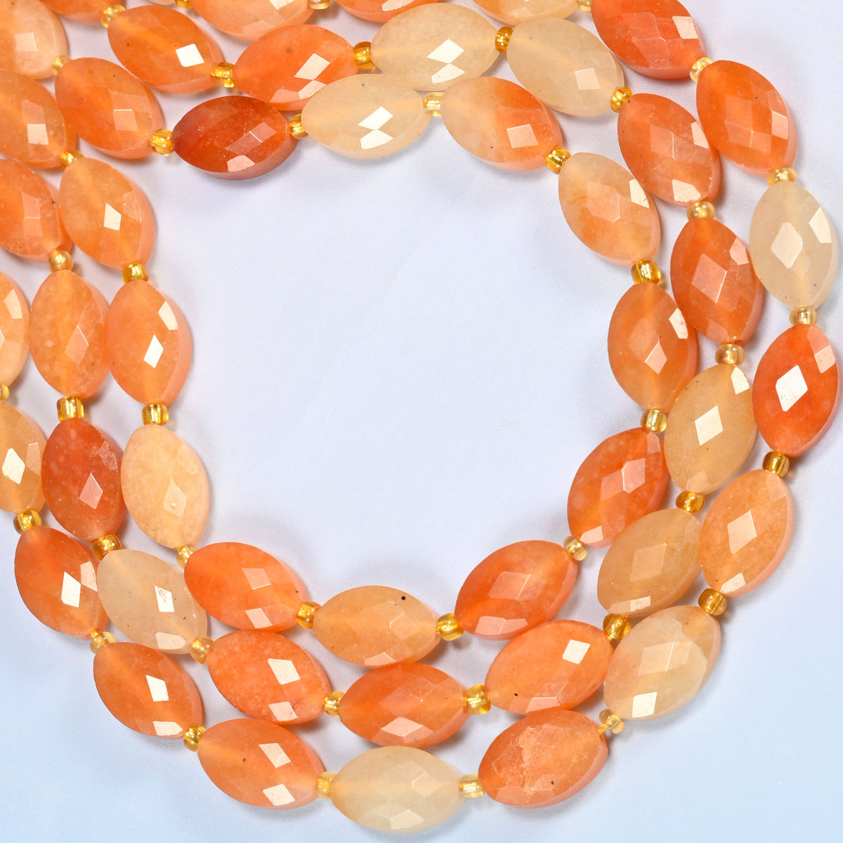 Red aventurine faceted flat oval beads curved into an open loop, peach, orange and cream beads